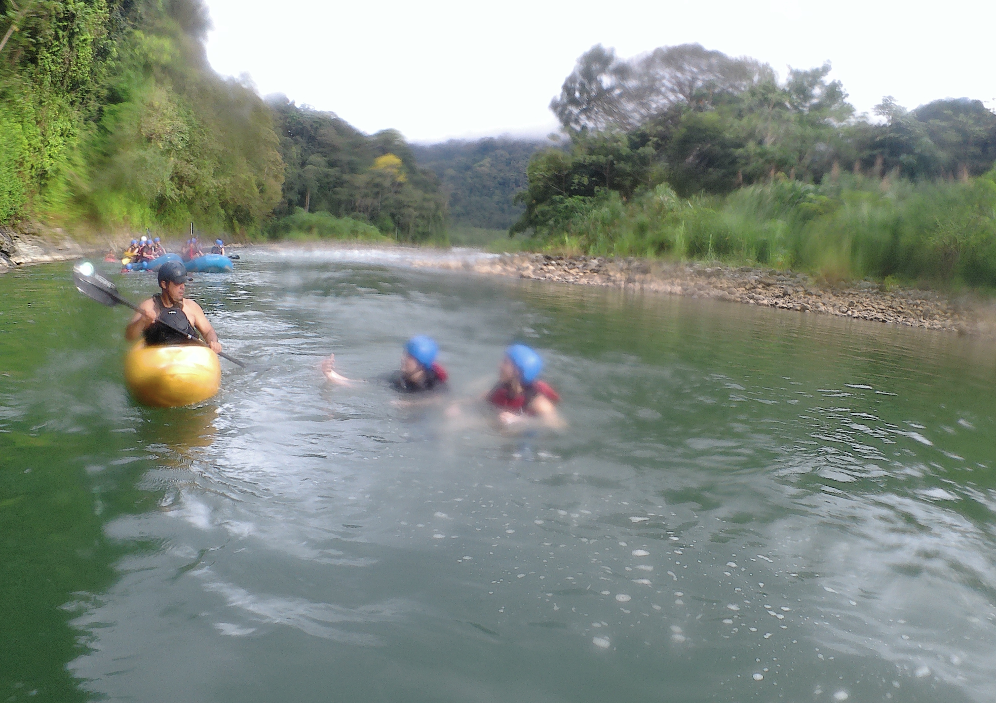 Kids floating in the river beside a kayak guide